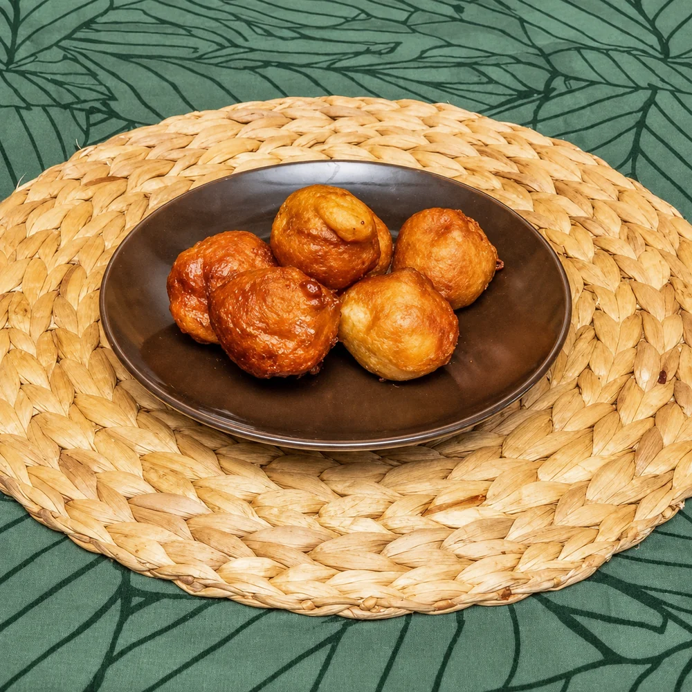 Five golden bofrot dough balls on a round brown plate